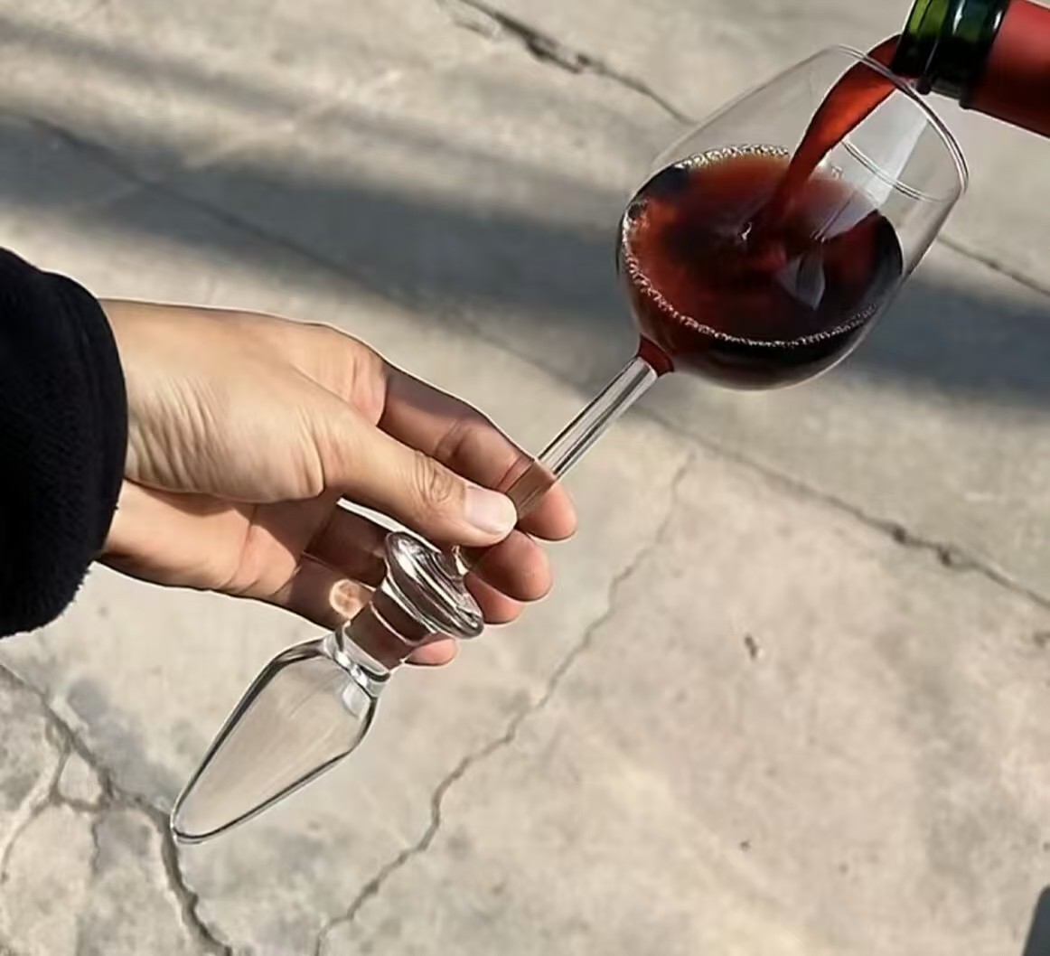 阳光下手持酒杯倒入红酒的生活方式照片